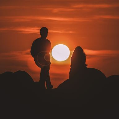 silhouette of two people looking at sunset