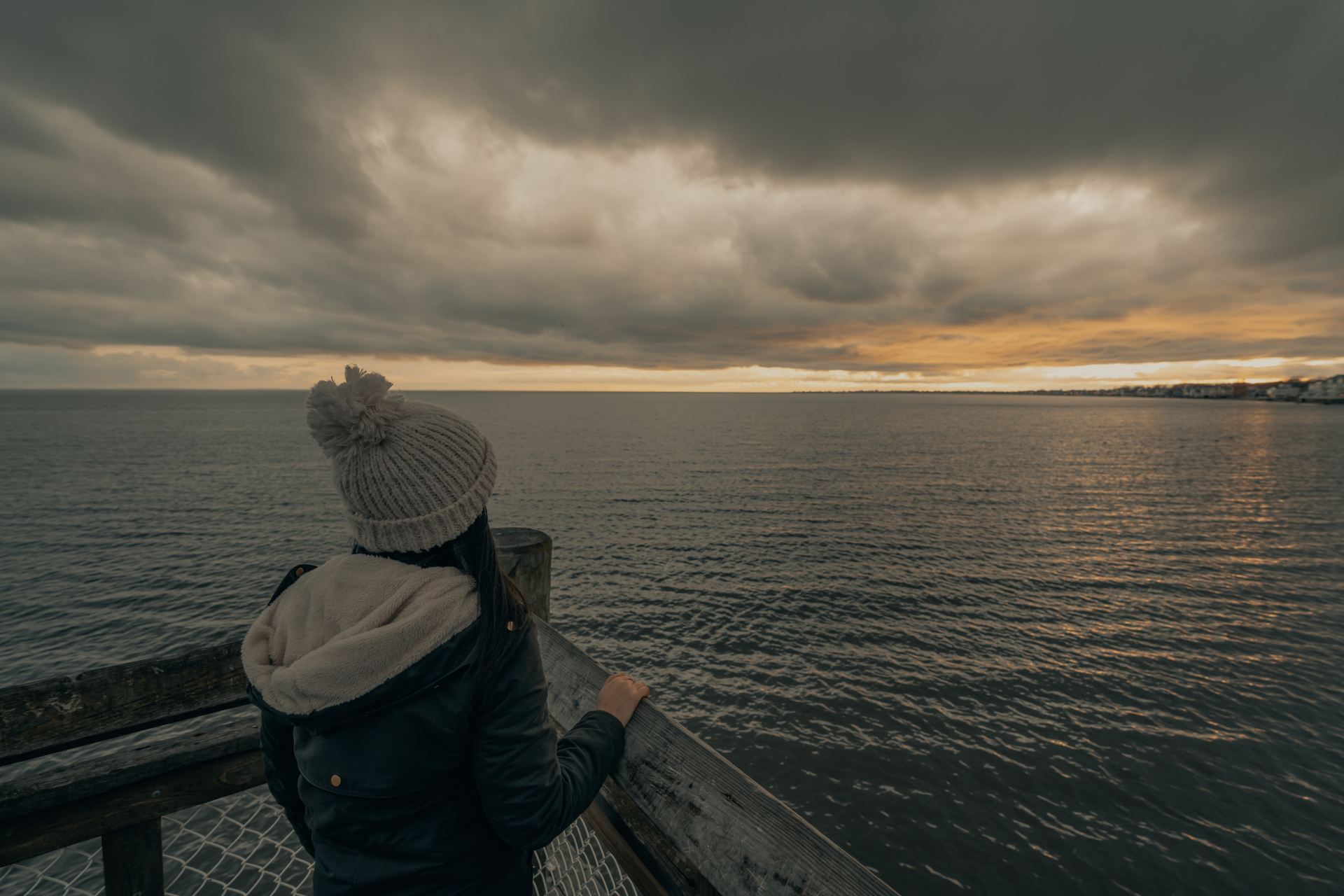 person in black jacket standing on wooden dock during daytime