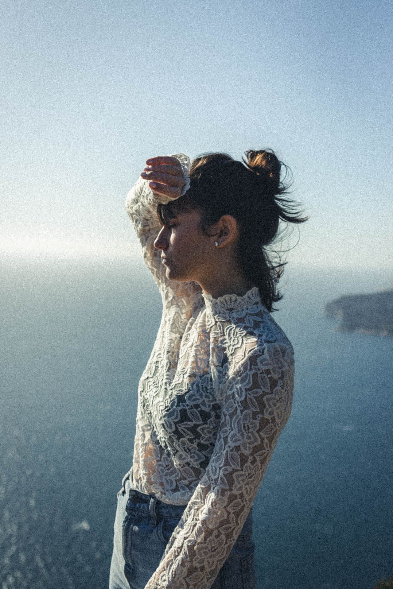 woman in white and blue floral shirt standing near body of water during daytime