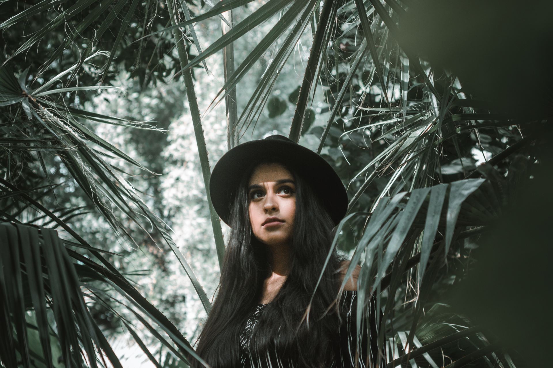 woman standing surrounded by palm leaves