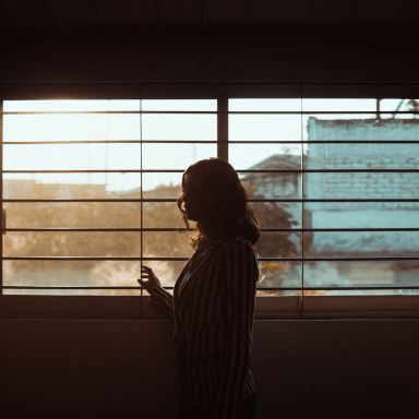 woman in white and black stripe shirt standing near window