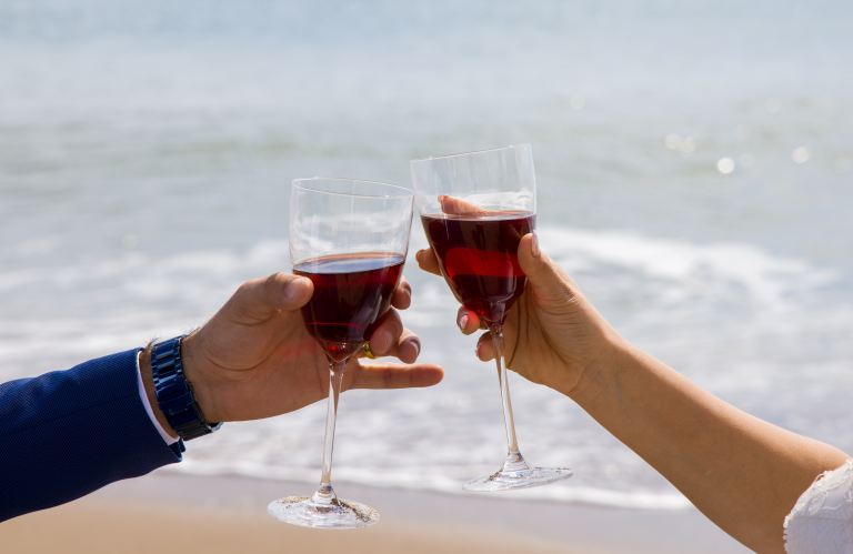 2 person holding clear wine glass with red wine during daytime