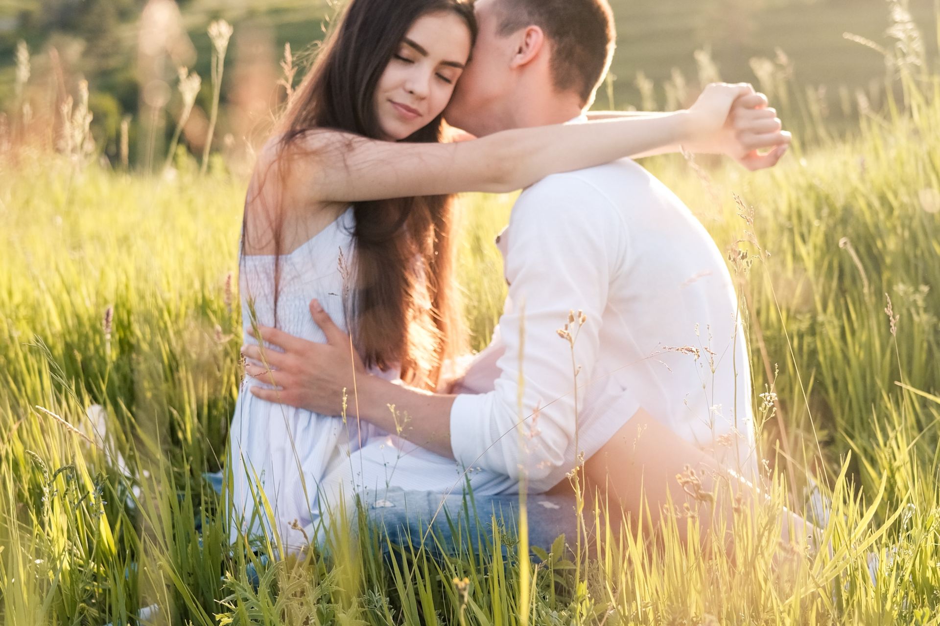 woman in white shirt sitting on green grass field during daytime