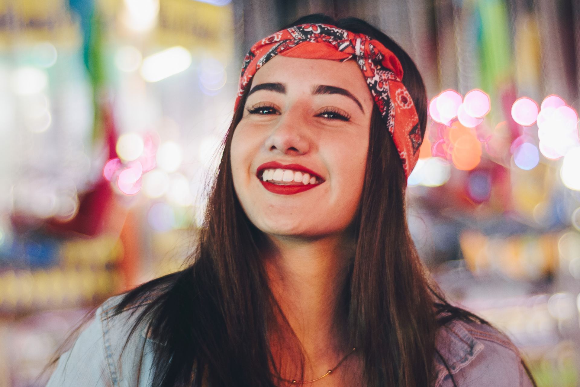 selective focus photography of smiling woman wearing red and black bandana