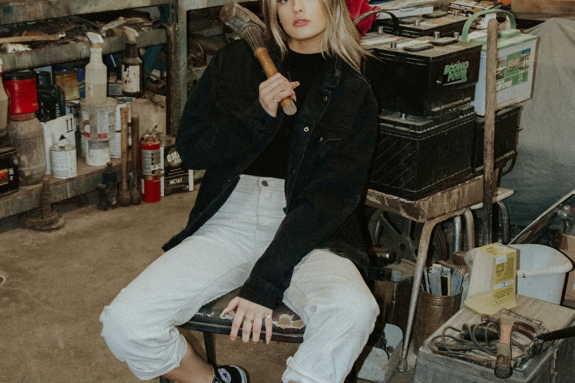 woman in black leather jacket and white pants sitting on black chair