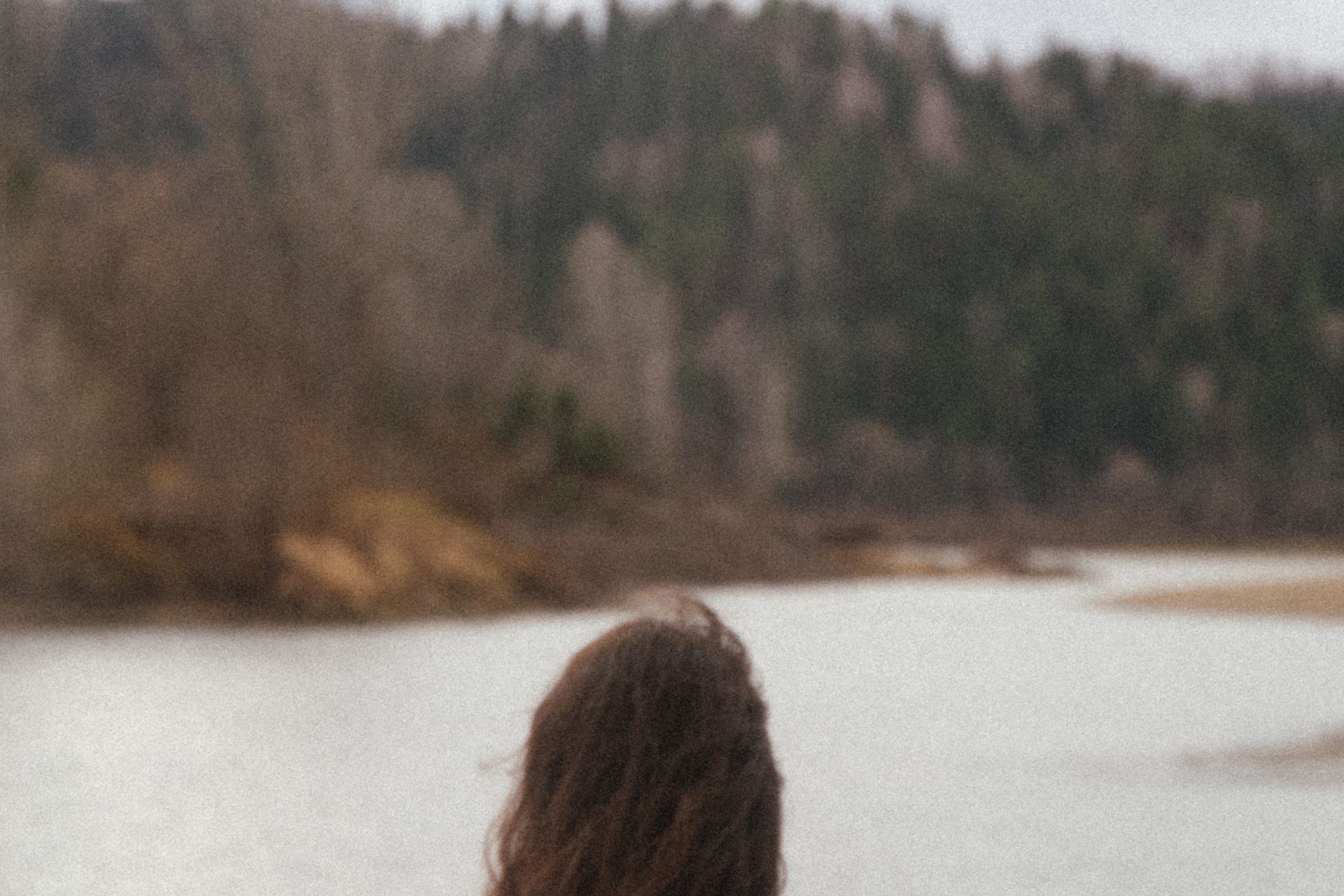 woman in white shirt sitting on white textile near body of water during daytime
