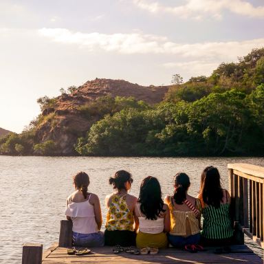 group of people sitting on brown wooden bench near body of water during daytime