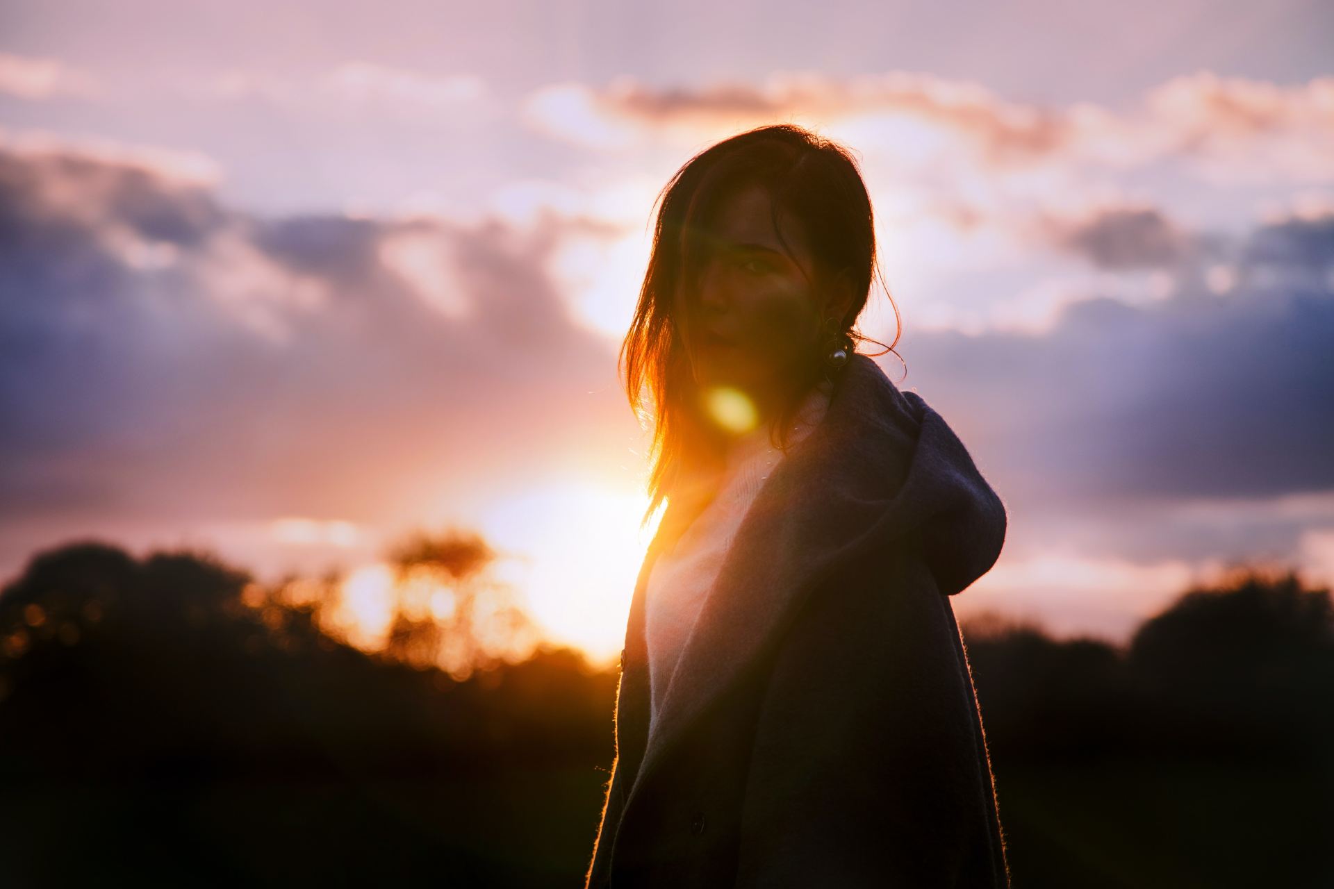 woman wearing gray hoodie during sunset