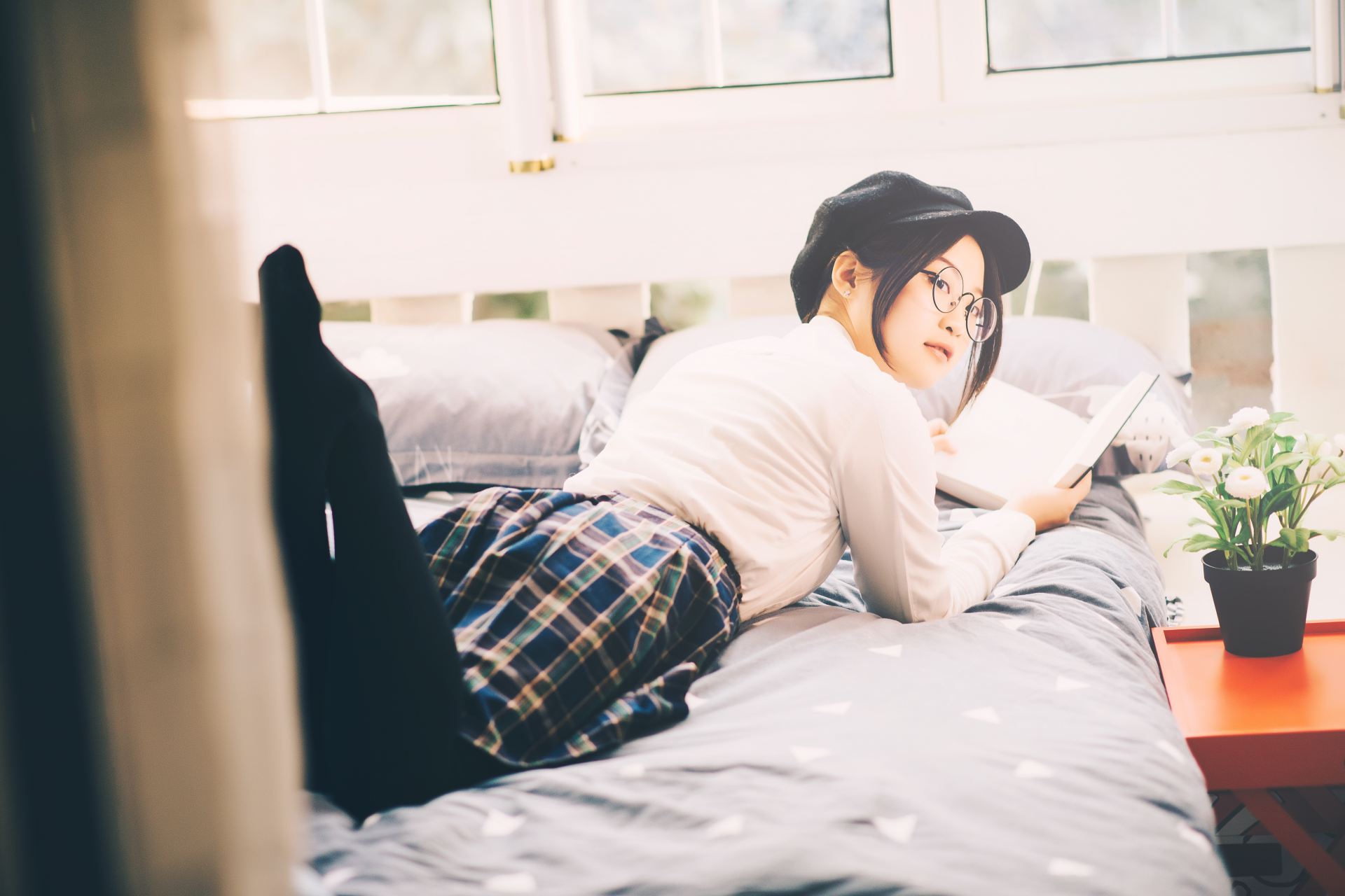 woman reading book while laying on bed