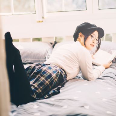 woman reading book while laying on bed
