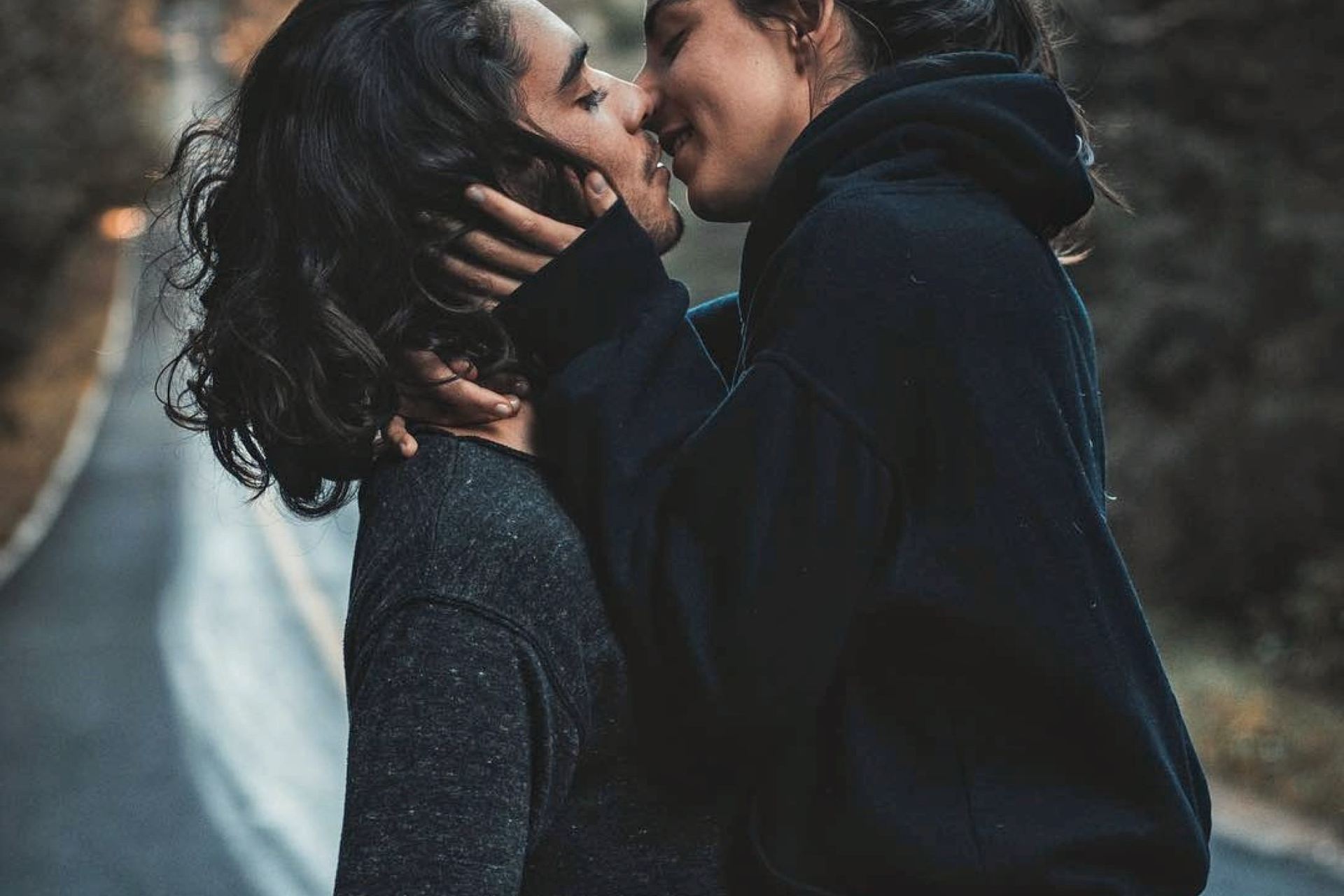 man and woman kissing and standing on road