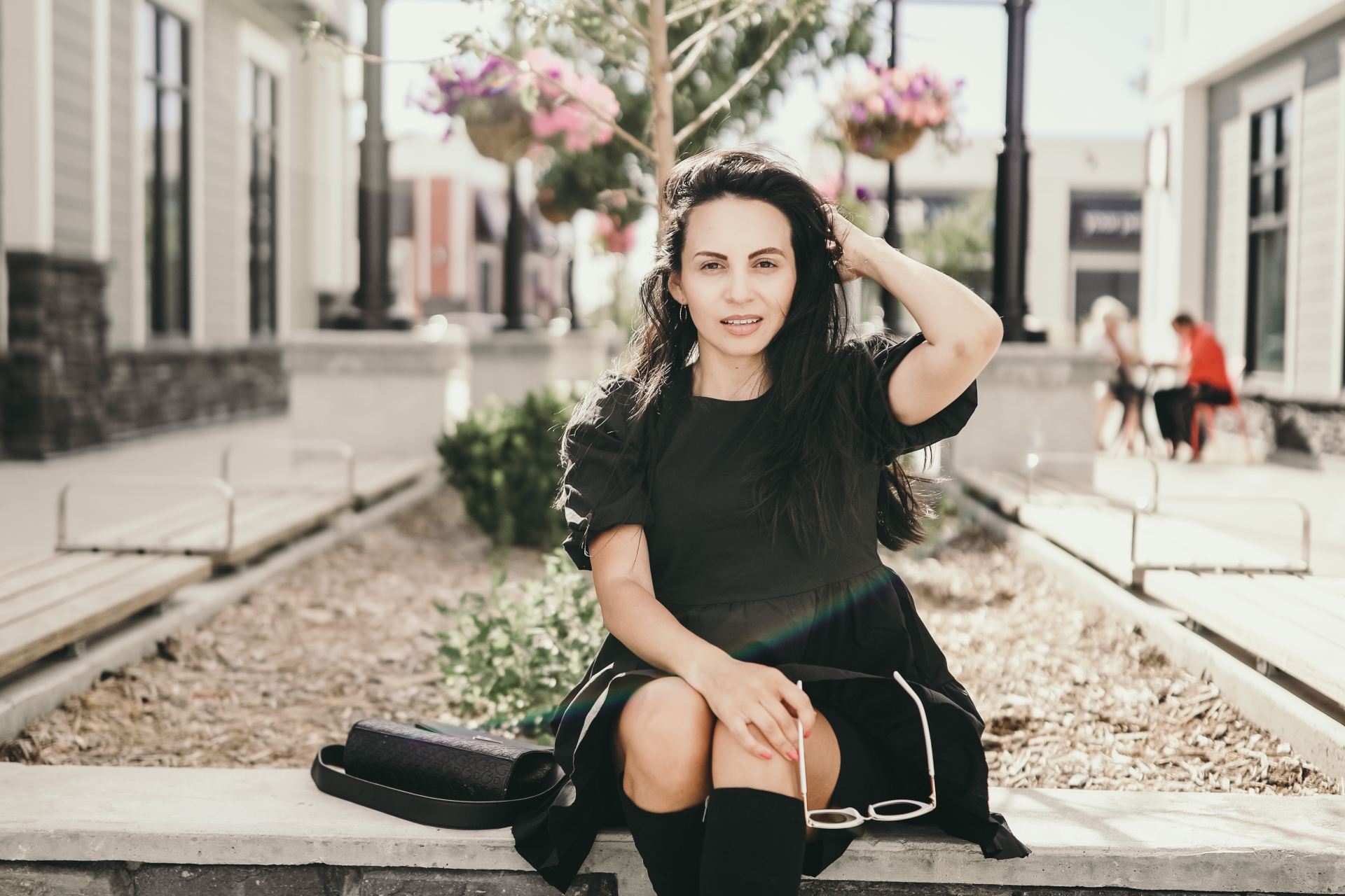 woman in black long sleeve shirt and black pants sitting on concrete bench during daytime