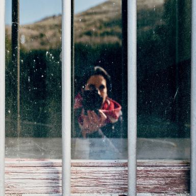 girl in red and white jacket standing beside window