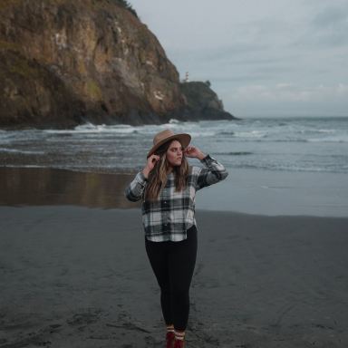 woman in black and white plaid long sleeve shirt standing on beach shore during daytime