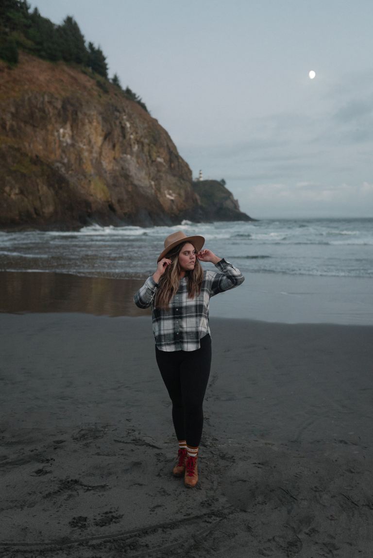 woman in black and white plaid long sleeve shirt standing on beach shore during daytime