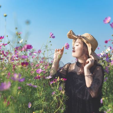 woman in black dress standing on flower field during daytime