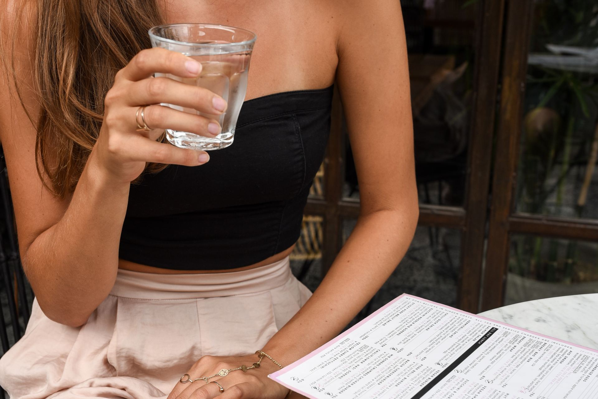 woman in black crop top holding clear rock glass