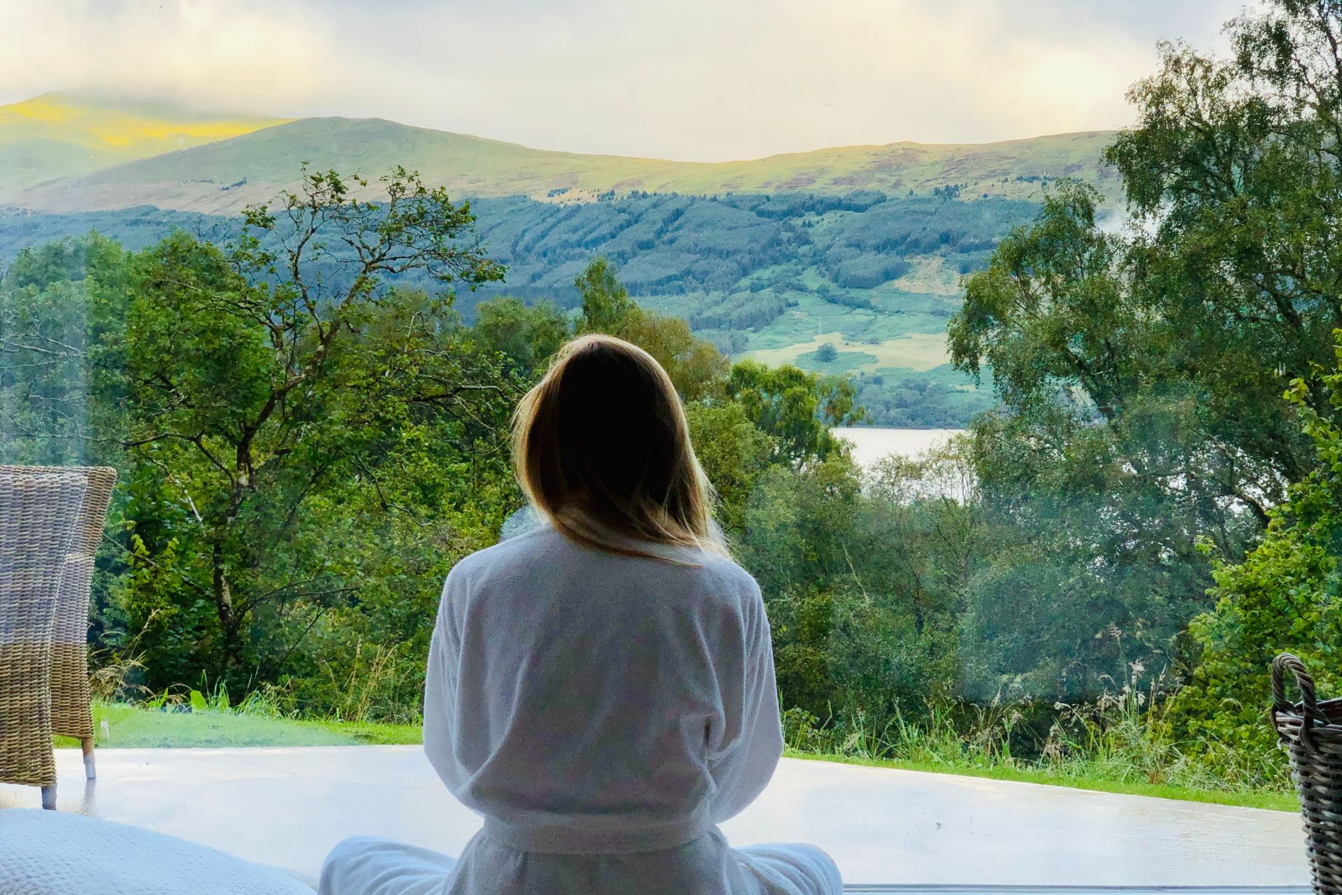 sitting woman in white robe looking at mountains during daytime