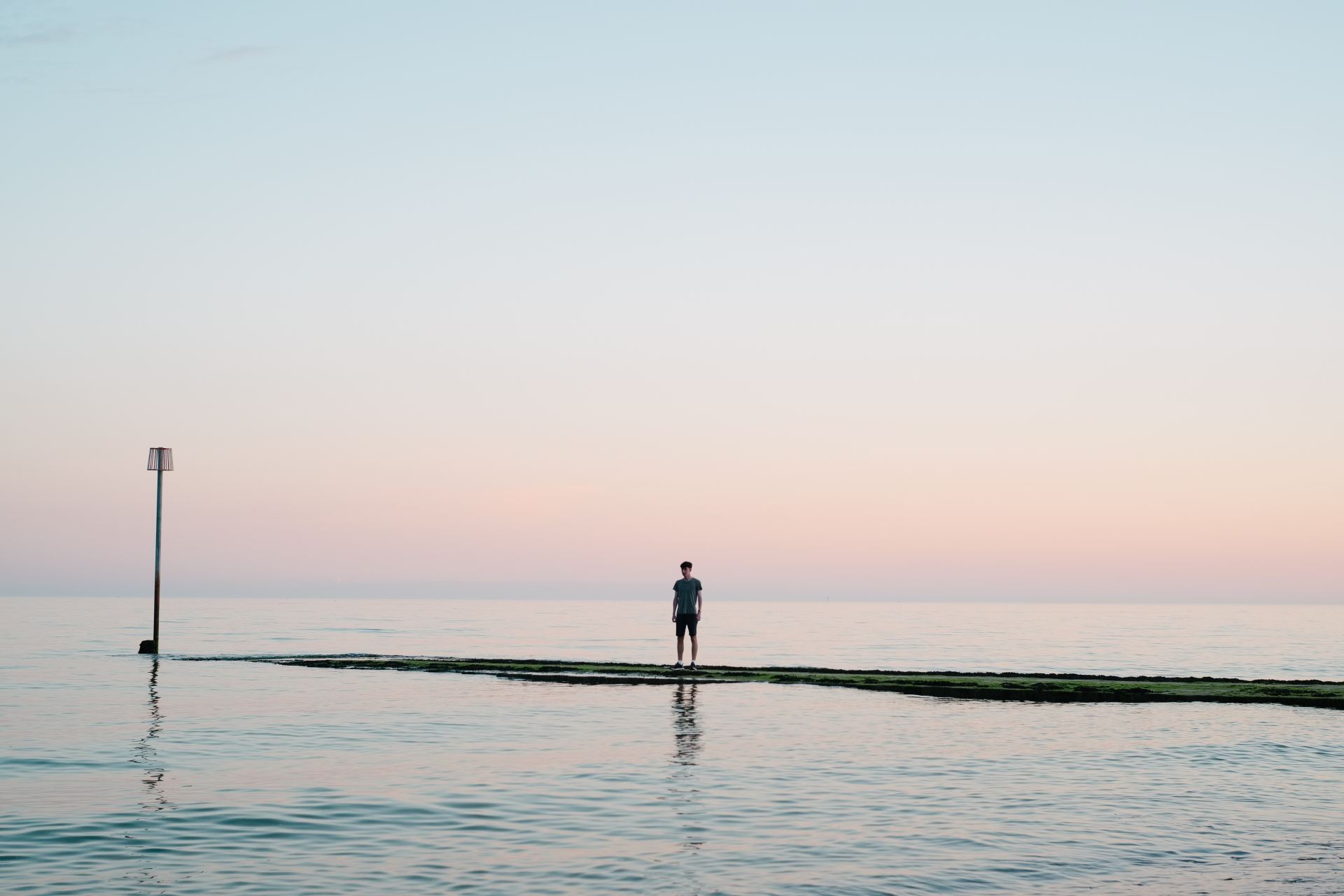 man standing on dock between body of water