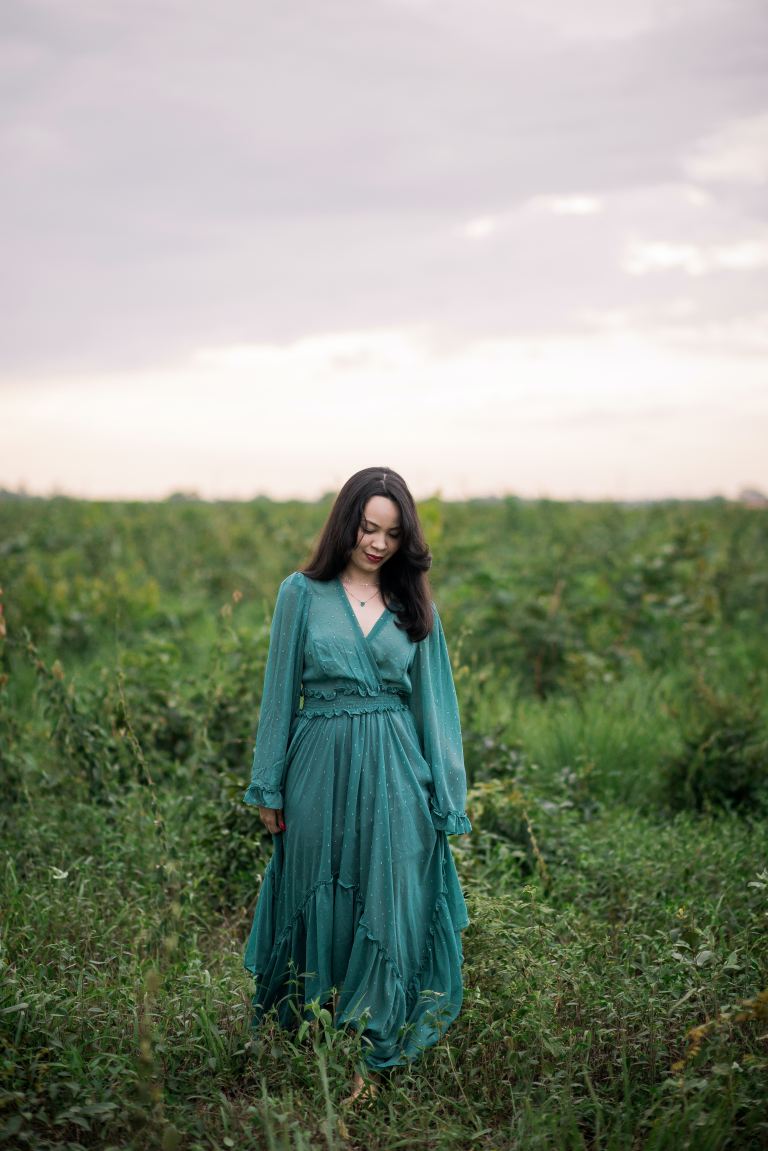 woman in green long sleeve dress standing on green grass field during daytime