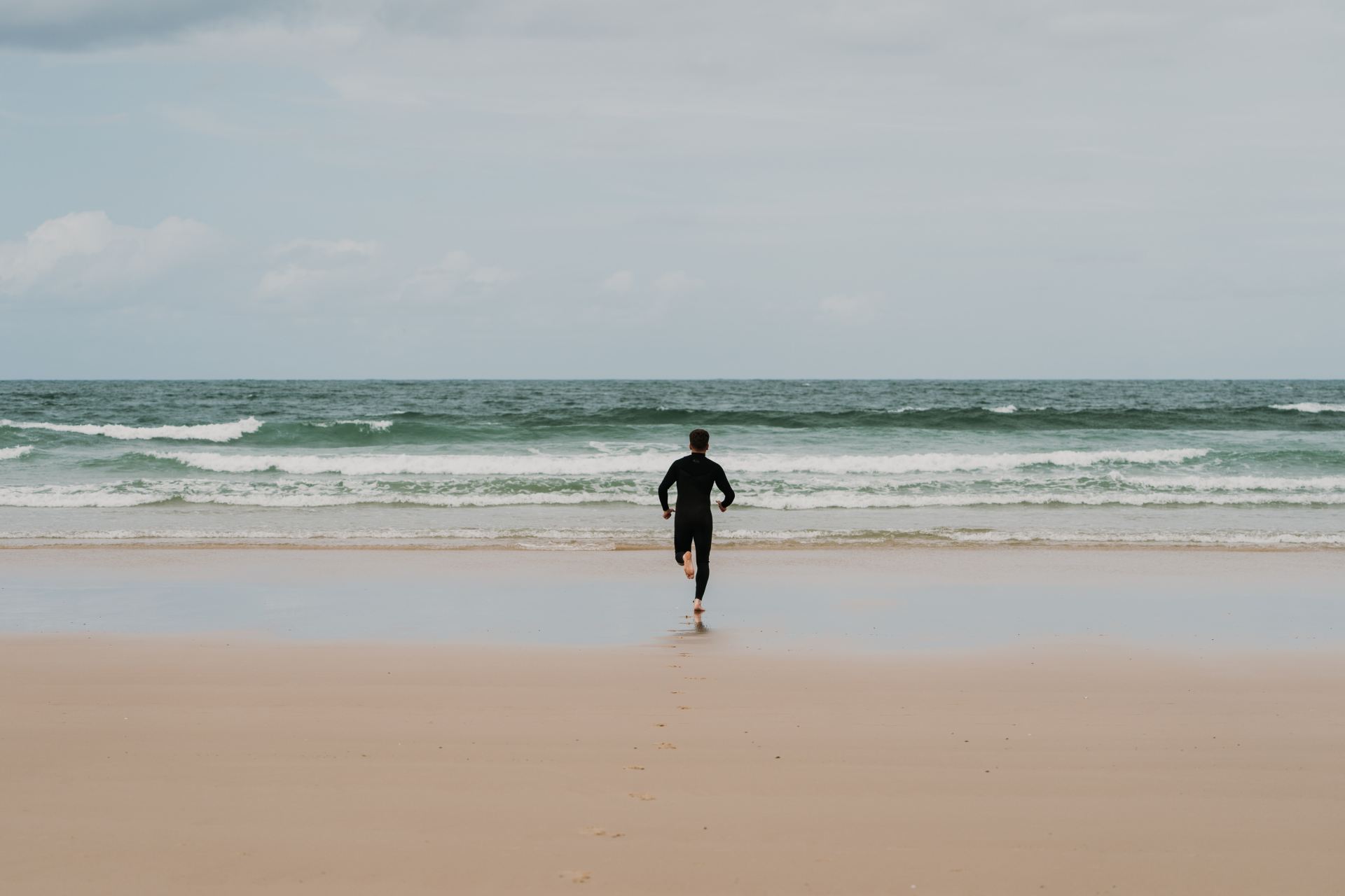 man in black shirt walking on beach during daytime