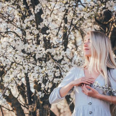 woman in white dress standing under white cherry blossom tree during daytime