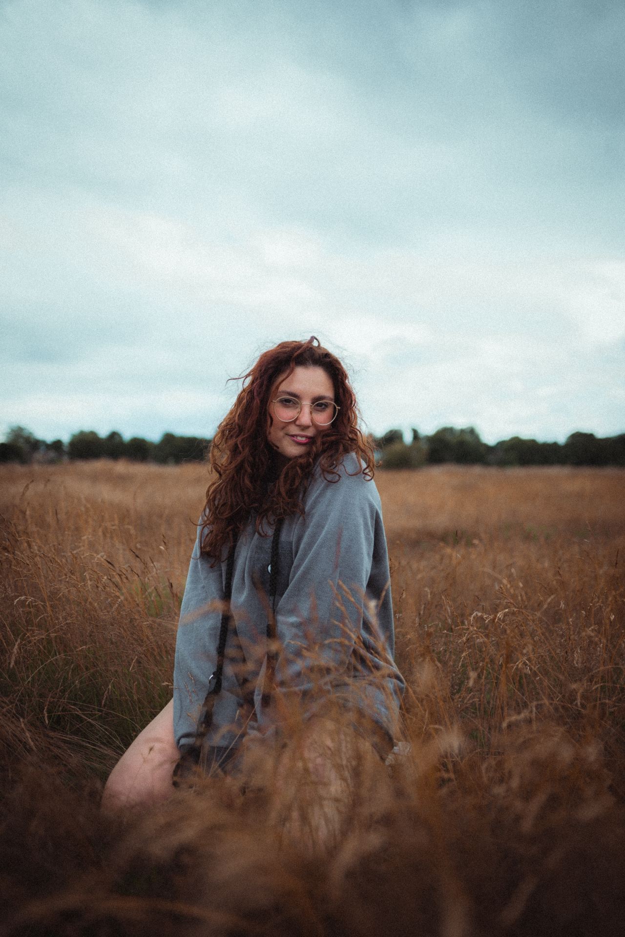 woman in blue long sleeve shirt sitting on brown grass field during daytime