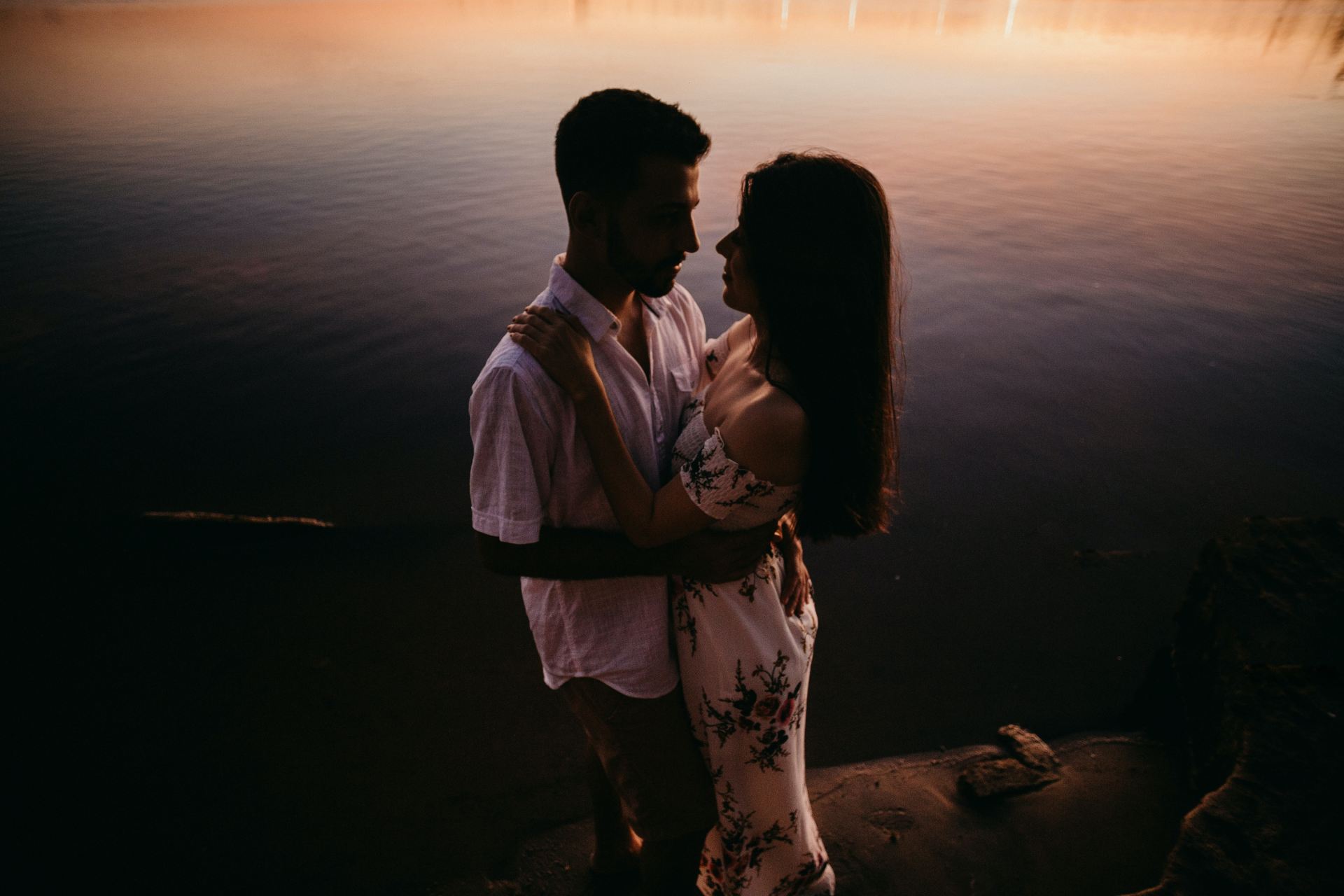 man and woman kissing beside body of water during daytime