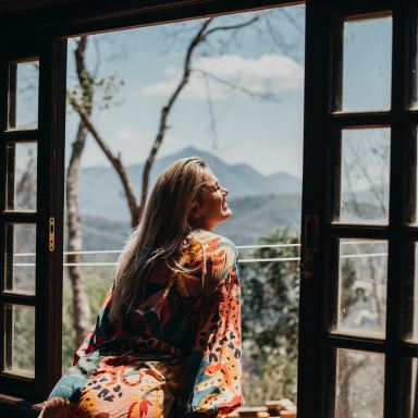 woman in red and white floral long sleeve shirt sitting on brown wooden chair