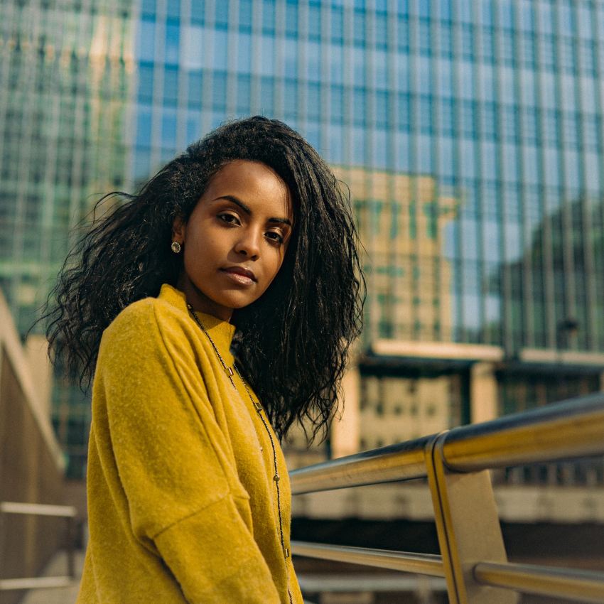 woman in yellow sweater standing beside brown metal railings